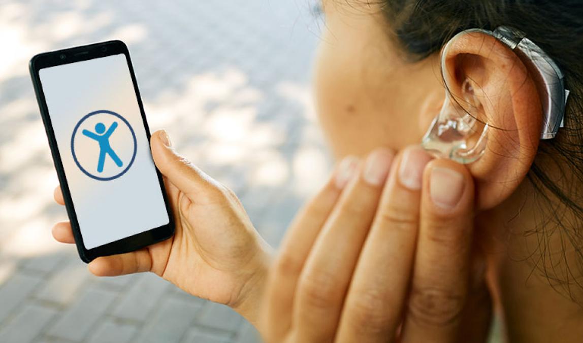 Image of a hearing impaired woman with a phone displaying the accessibility icon